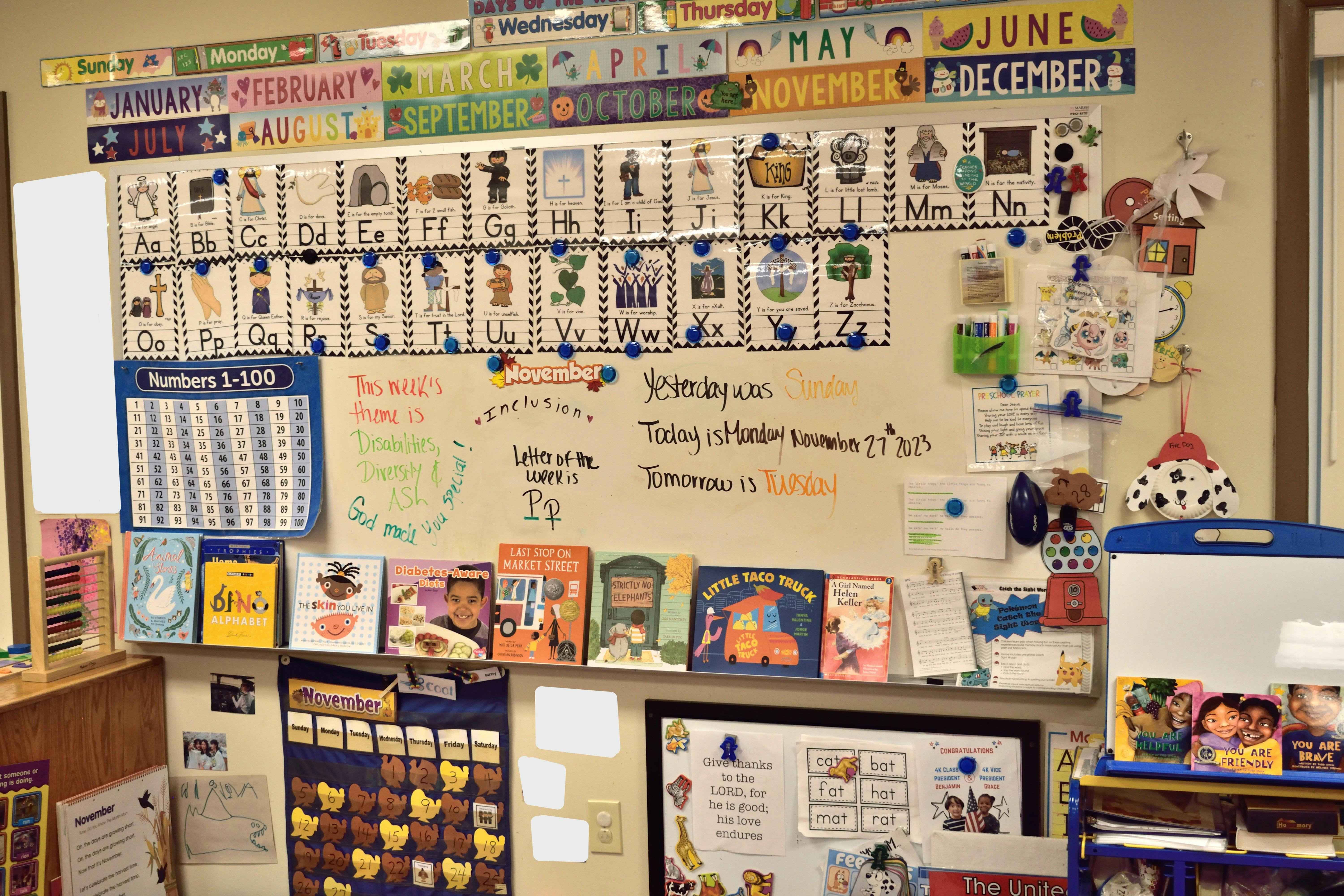 Classroom whiteboard with alphabet, numbers, and children's books displayed