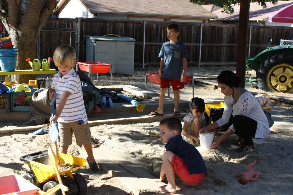 Adult and children playing in a sandbox