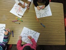 Three children coloring at a table