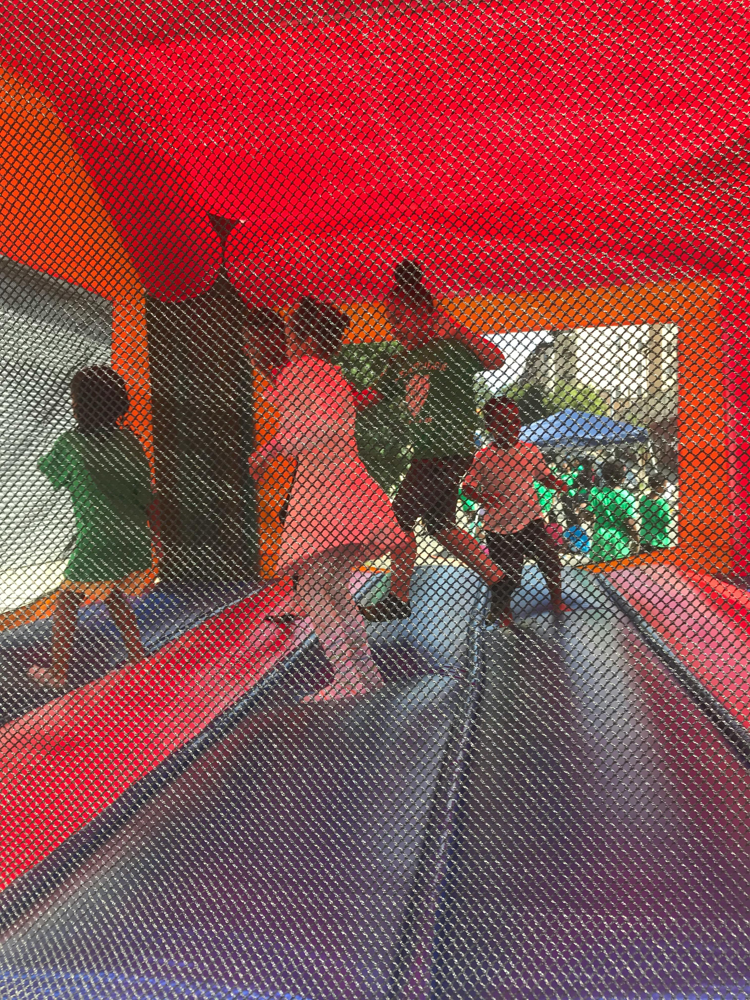 People and children playing inside a bounce house