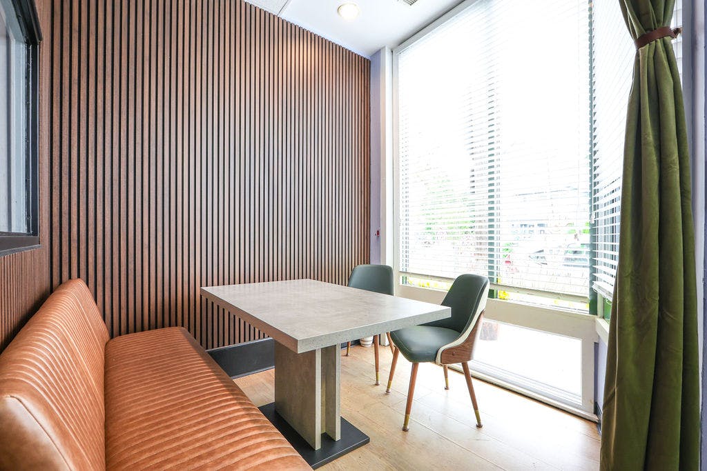 Dining area with a booth, table, and chairs next to a large window