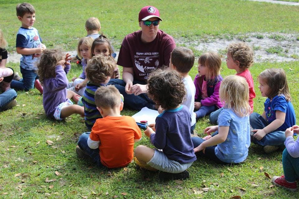 Adult and children sitting in a circle on grass