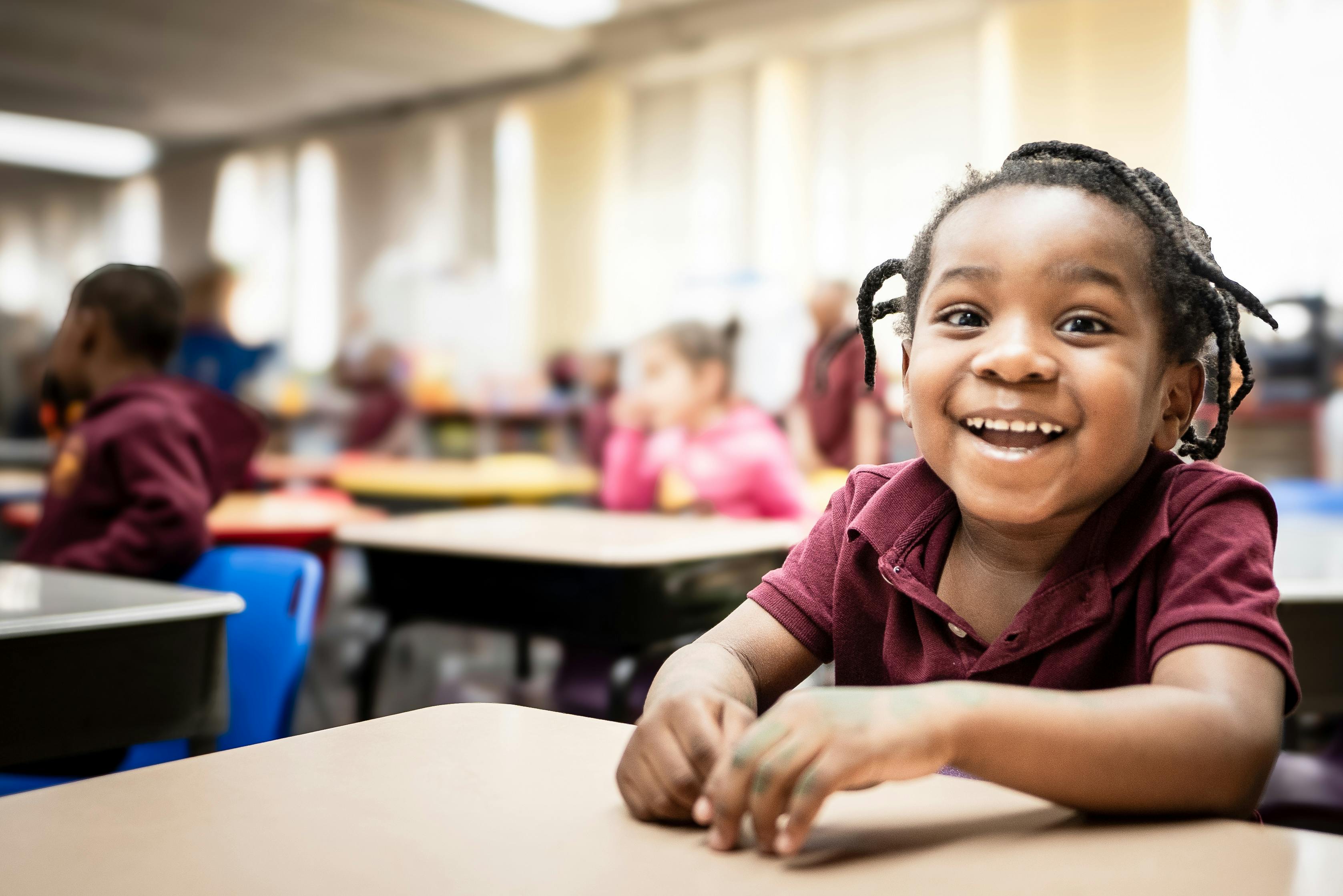 Child in a classroom smiling at a desk
