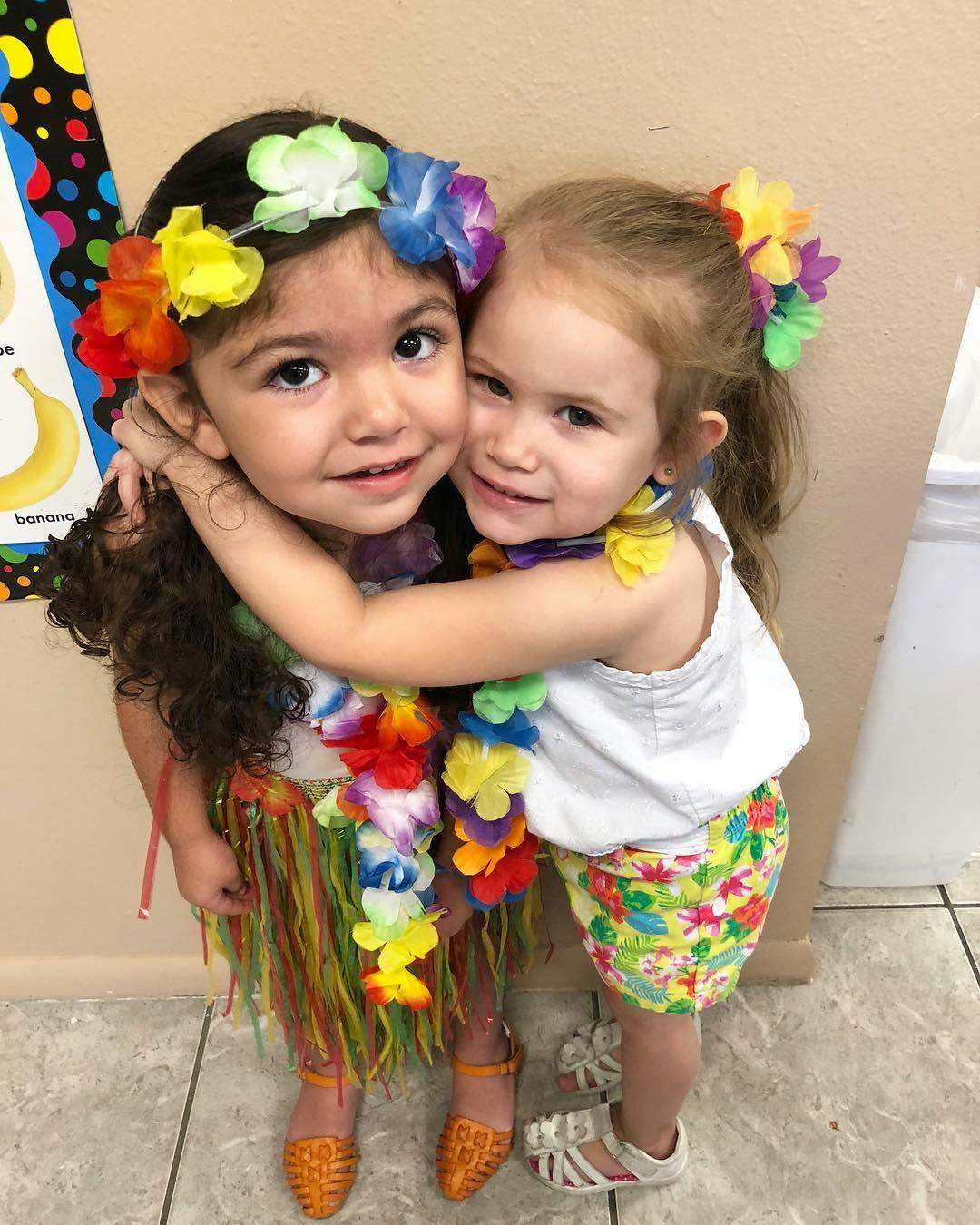 Two children in flower leis and headbands hugging