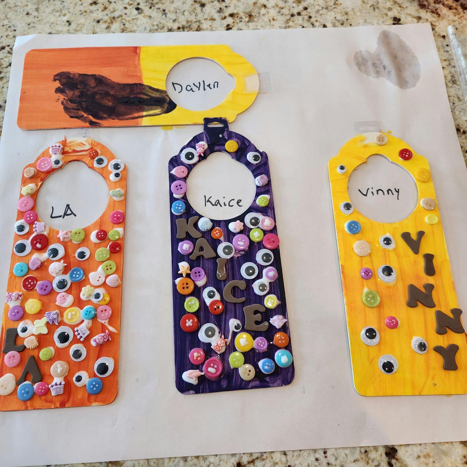 Four handmade door hangers decorated with buttons and googly eyes