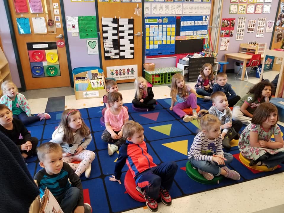 Group of children sitting on a colorful rug in a classroom