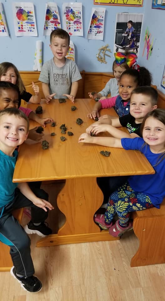 Children gathered around a table with small objects