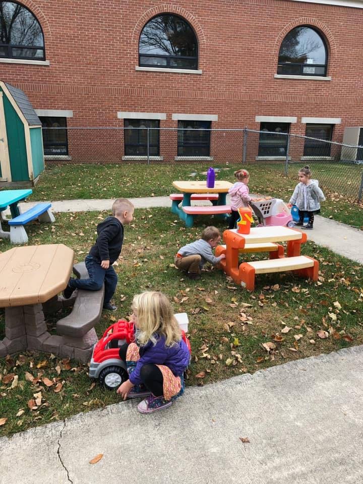 Children playing outdoors with toys and picnic tables