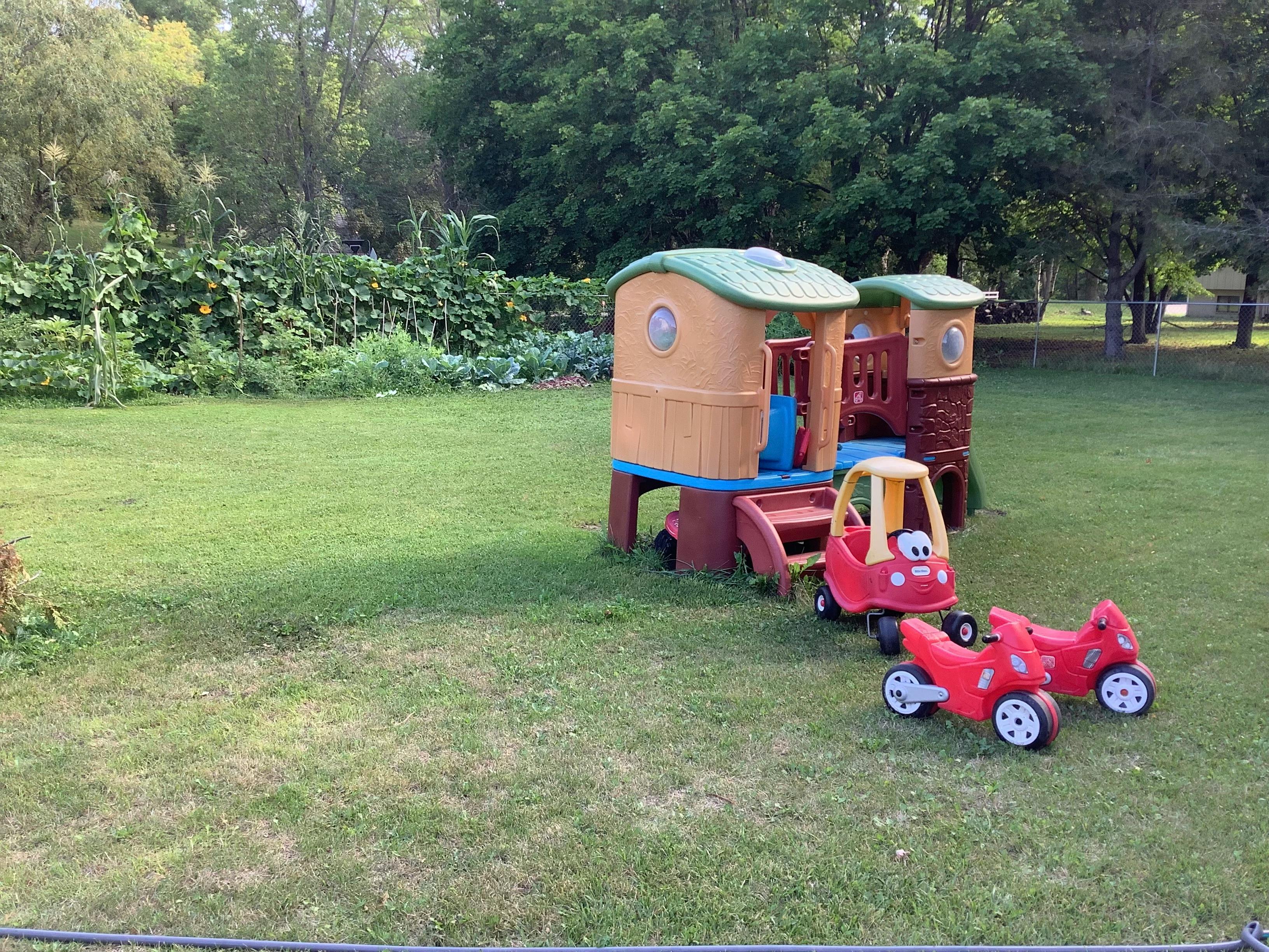 Playhouse and toy cars on a grassy lawn