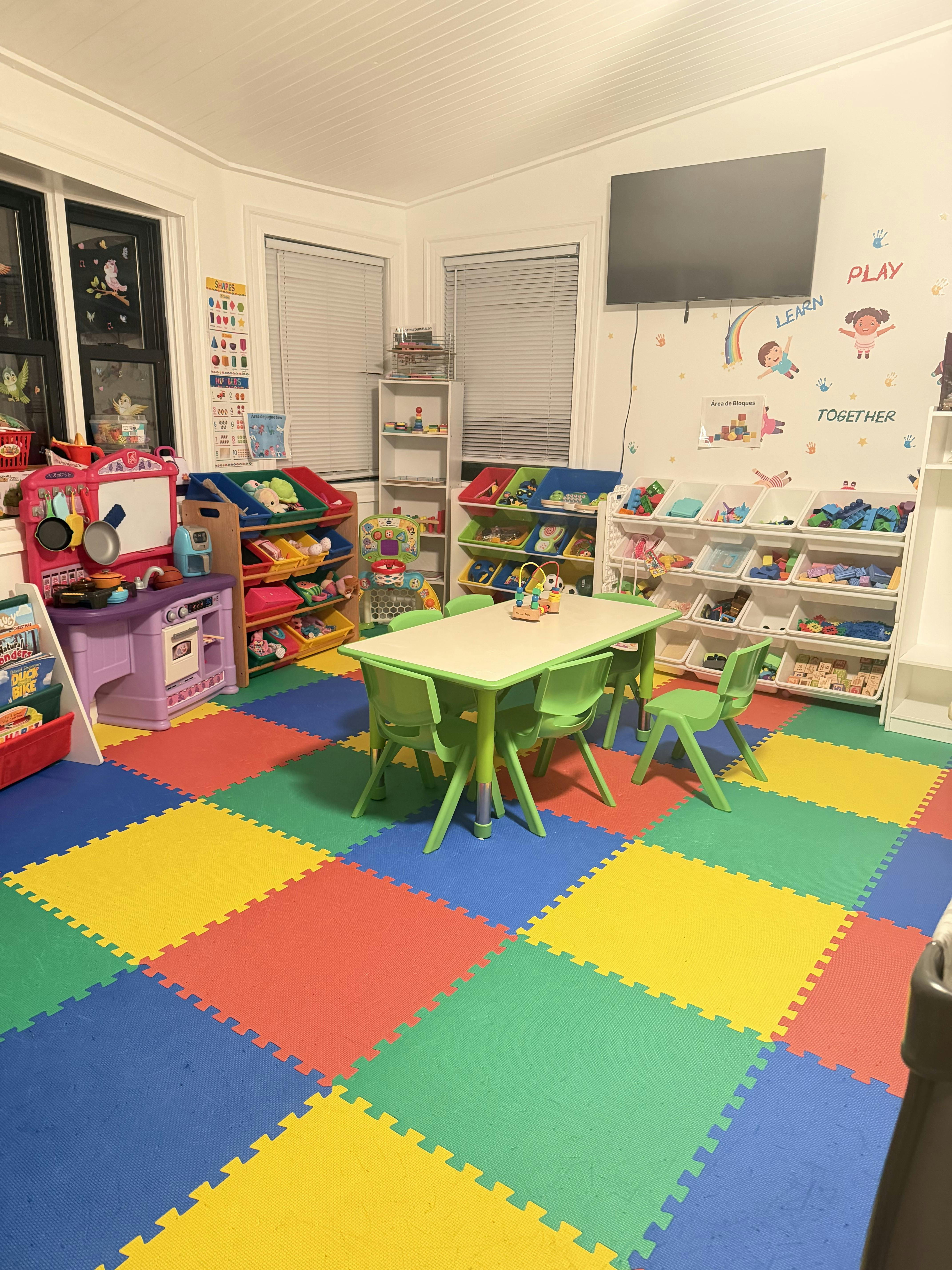 Children playroom with toy storage shelves, table, and colorful foam floor mats