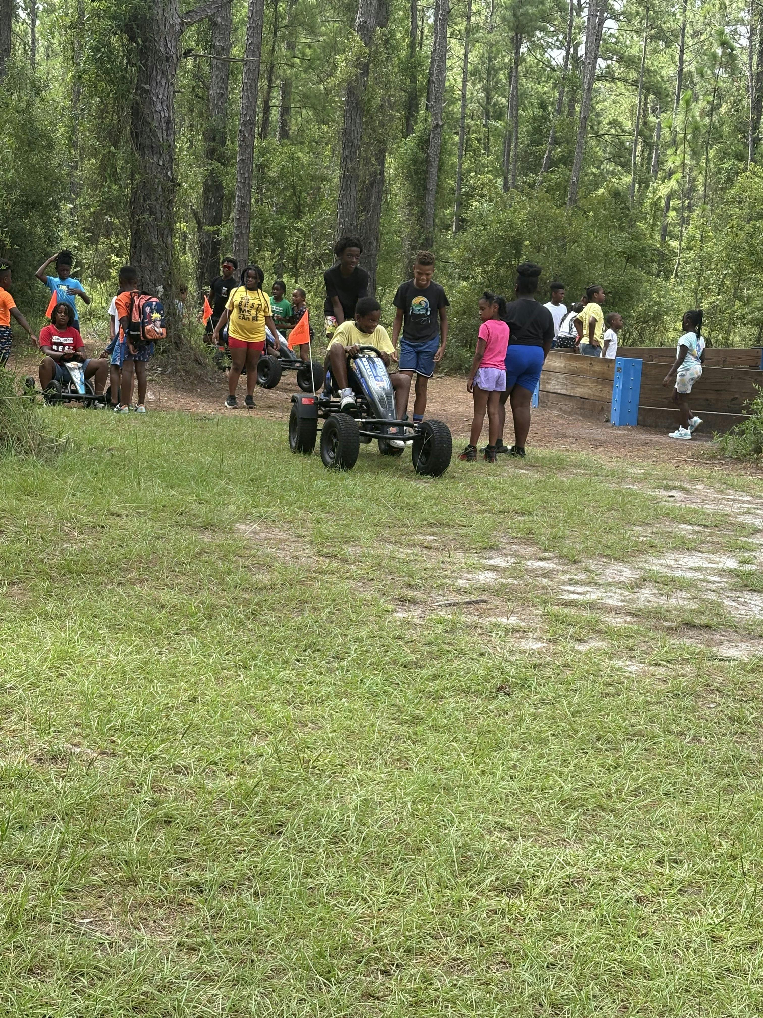 Group of children and teens playing with pedal go-karts outdoors