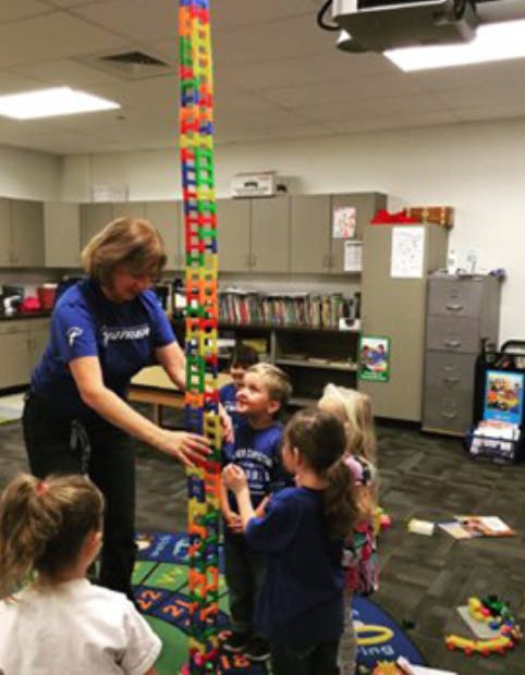 Adult and children building a tall tower with colorful blocks