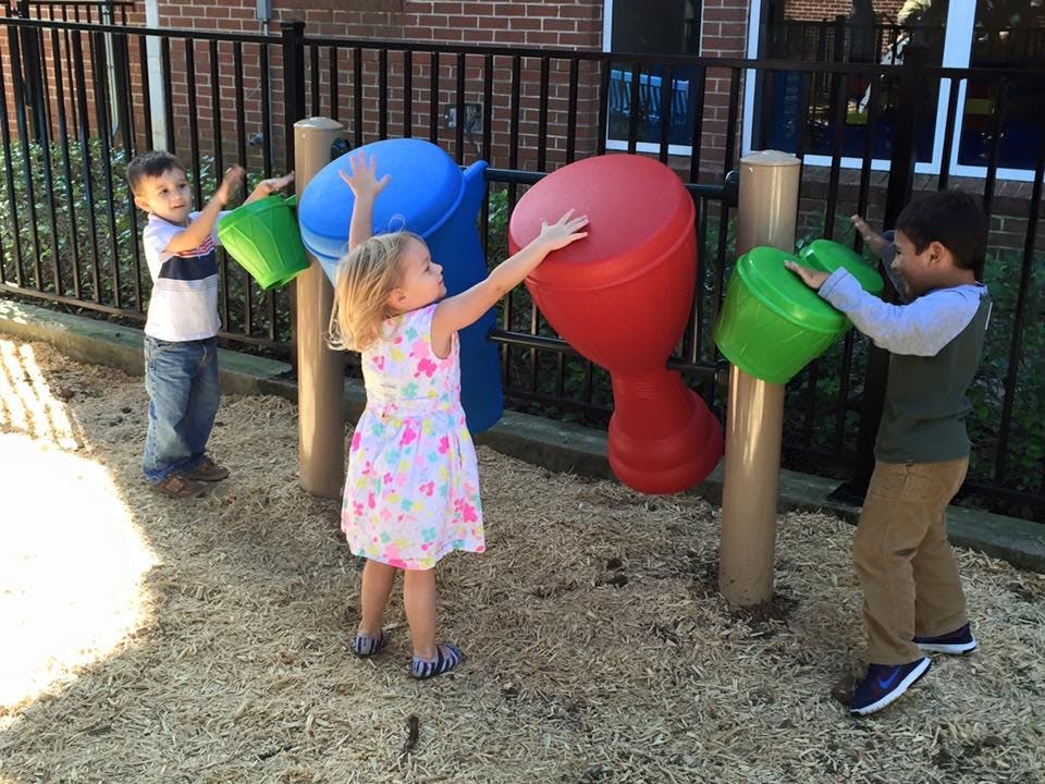 Three children playing with colorful outdoor musical instruments