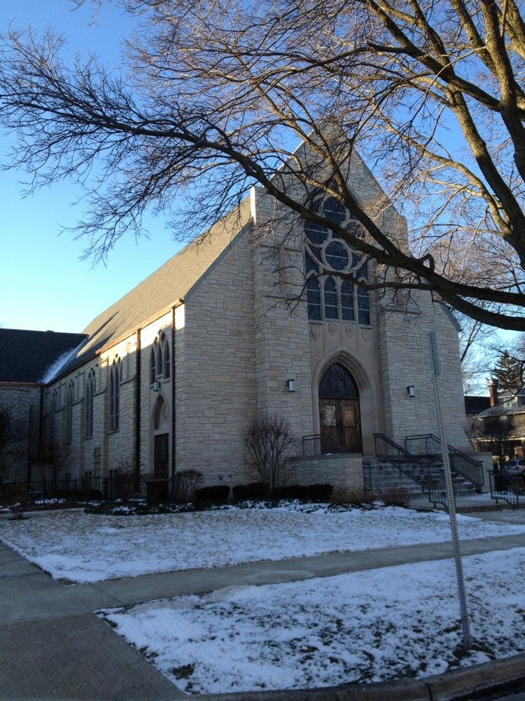 Stone church building with a large arched entrance and circular window