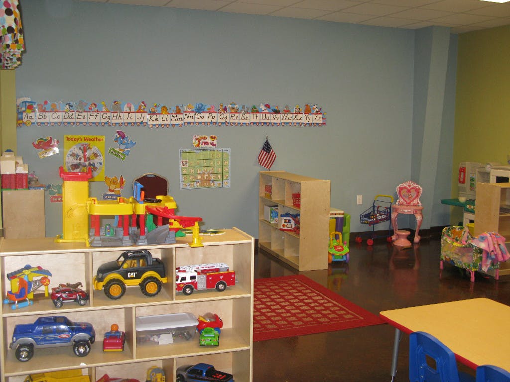 Playroom with shelves of toys, a red rug, and small tables