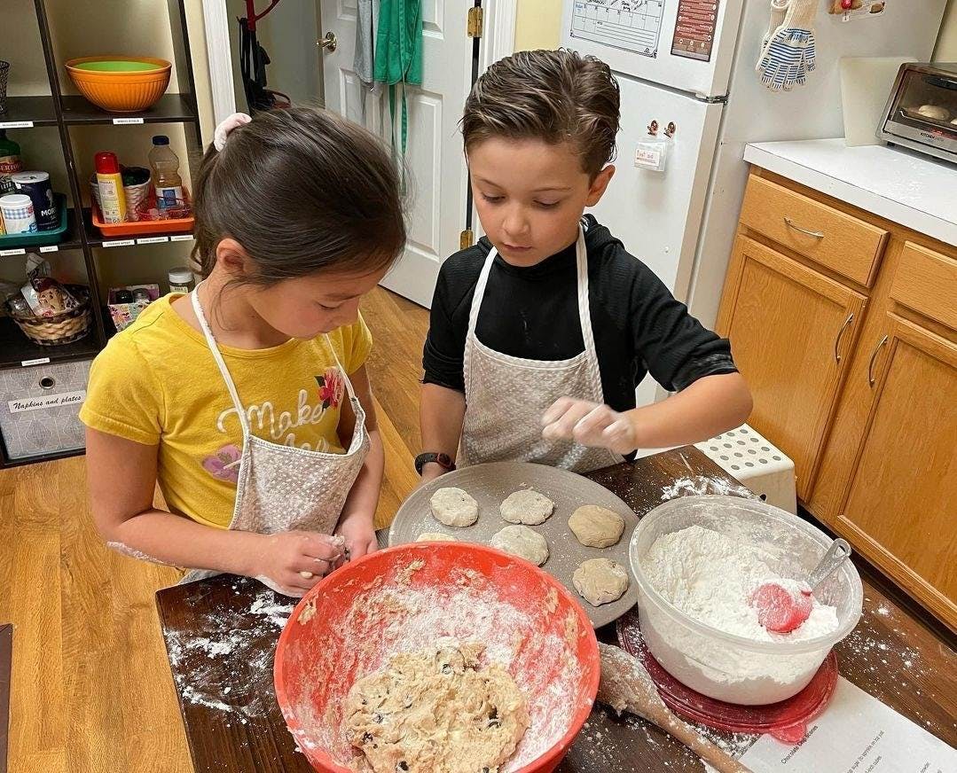 Two children in aprons baking in a kitchen