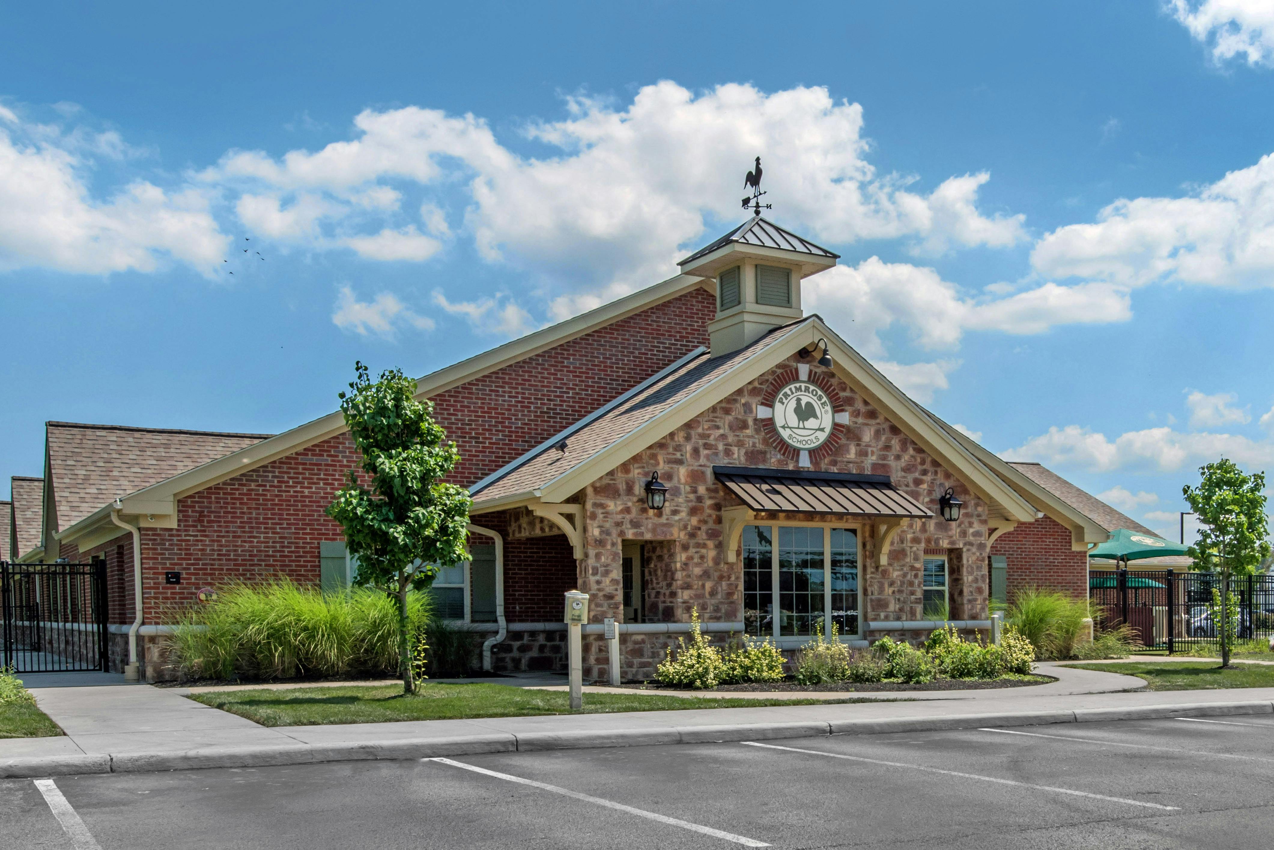 Brick and stone building with a sign that says Primrose Schools and a rooster weathervane