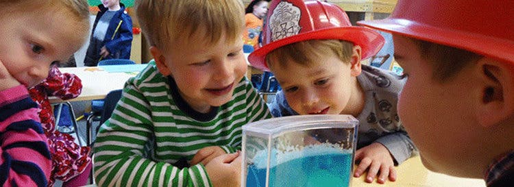 Children looking at a container with blue liquid