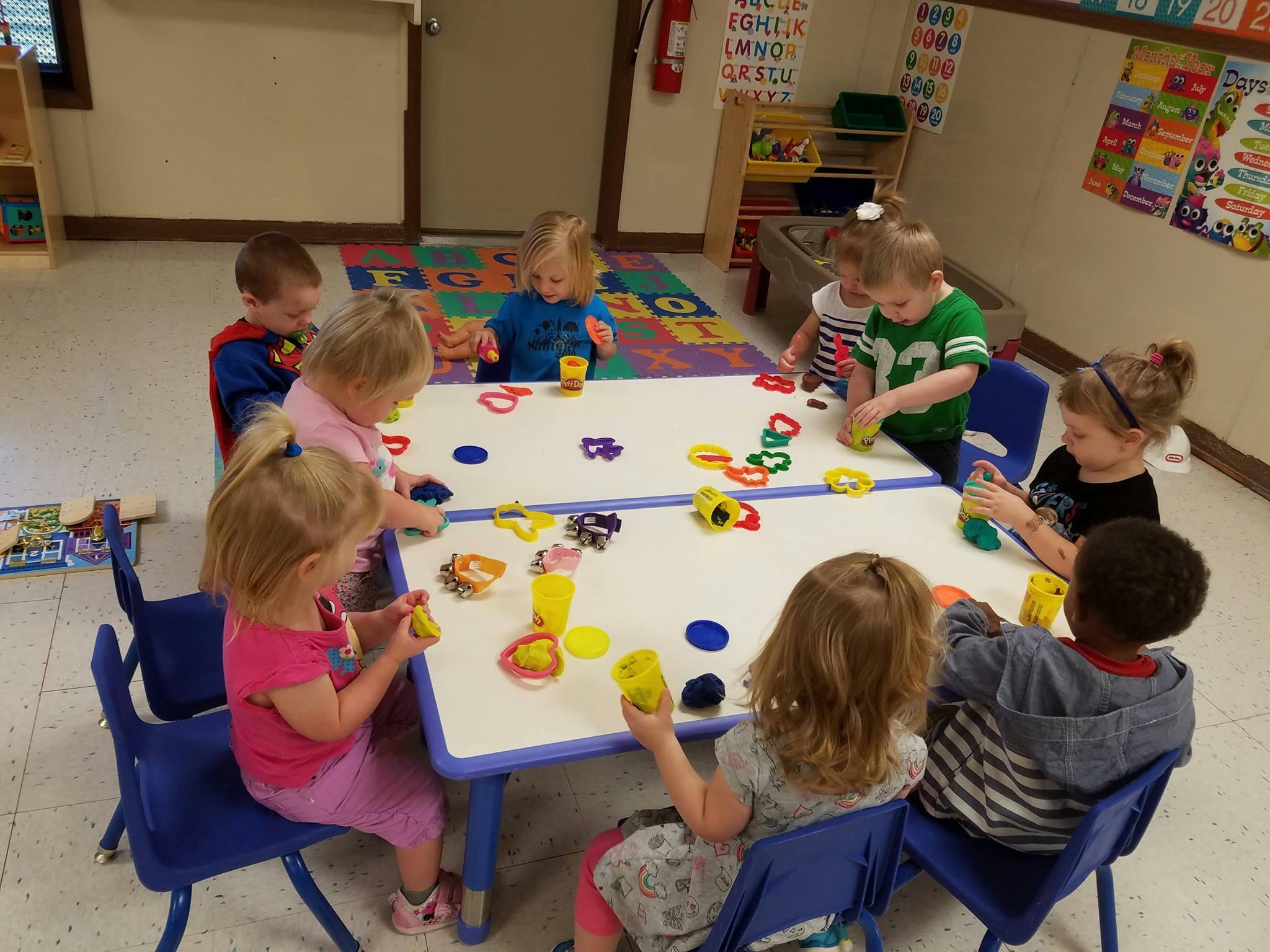 Children playing with colorful dough and cookie cutters at a table