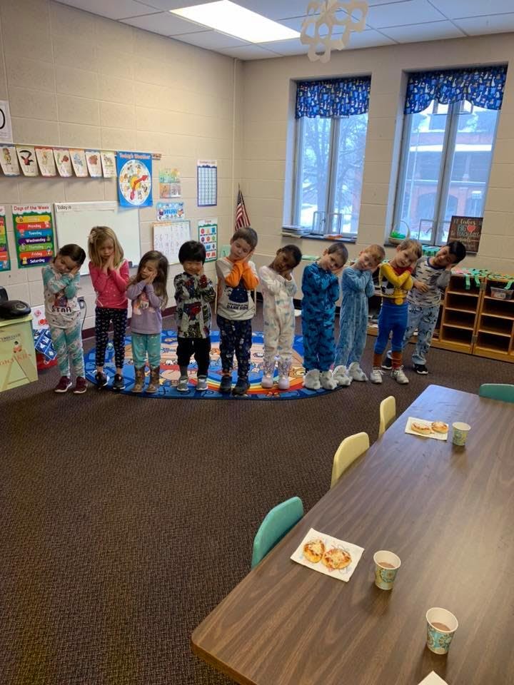 Children in pajamas standing in a line in a classroom