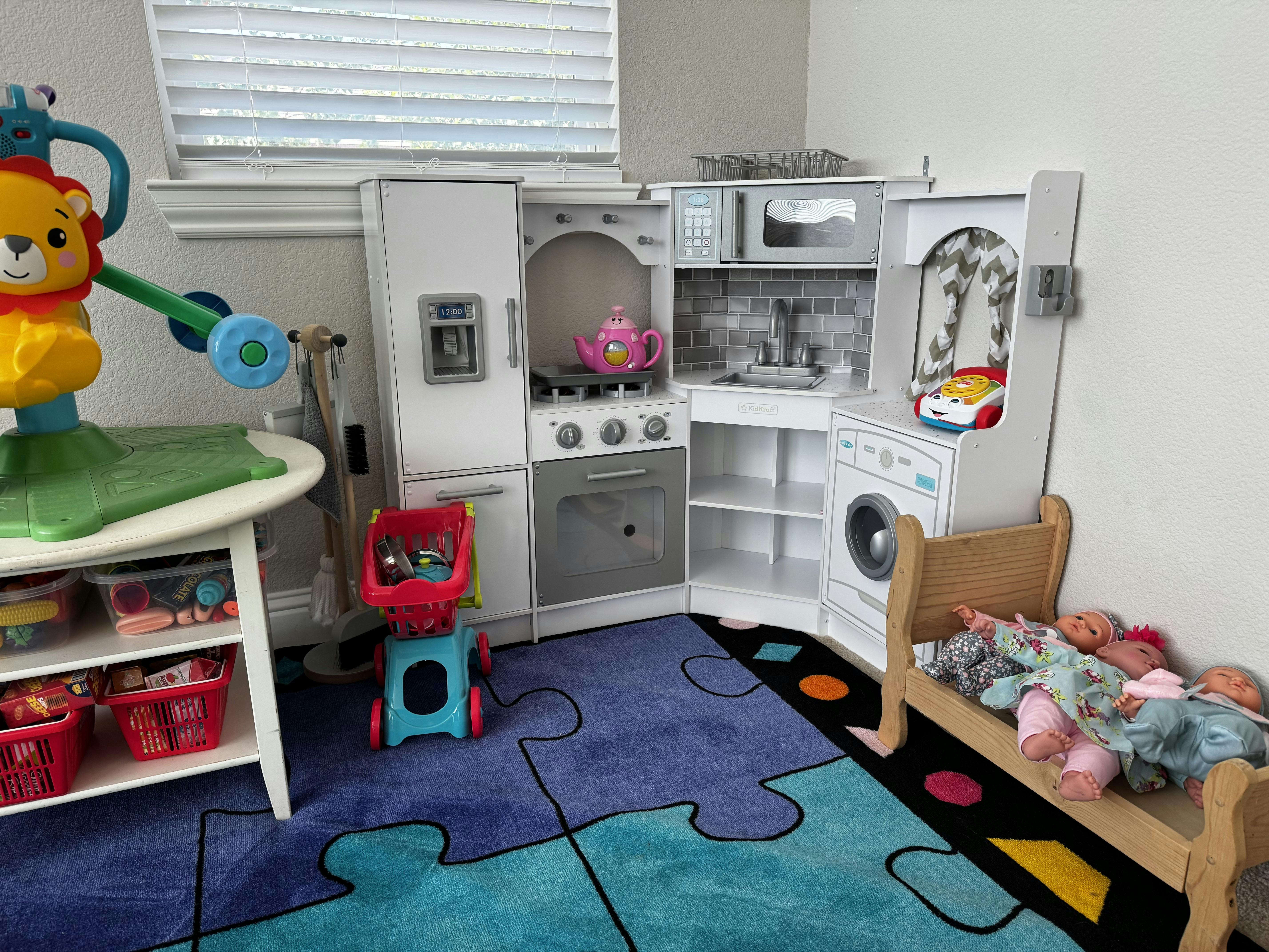 Children's play kitchen with a toy bed and dolls