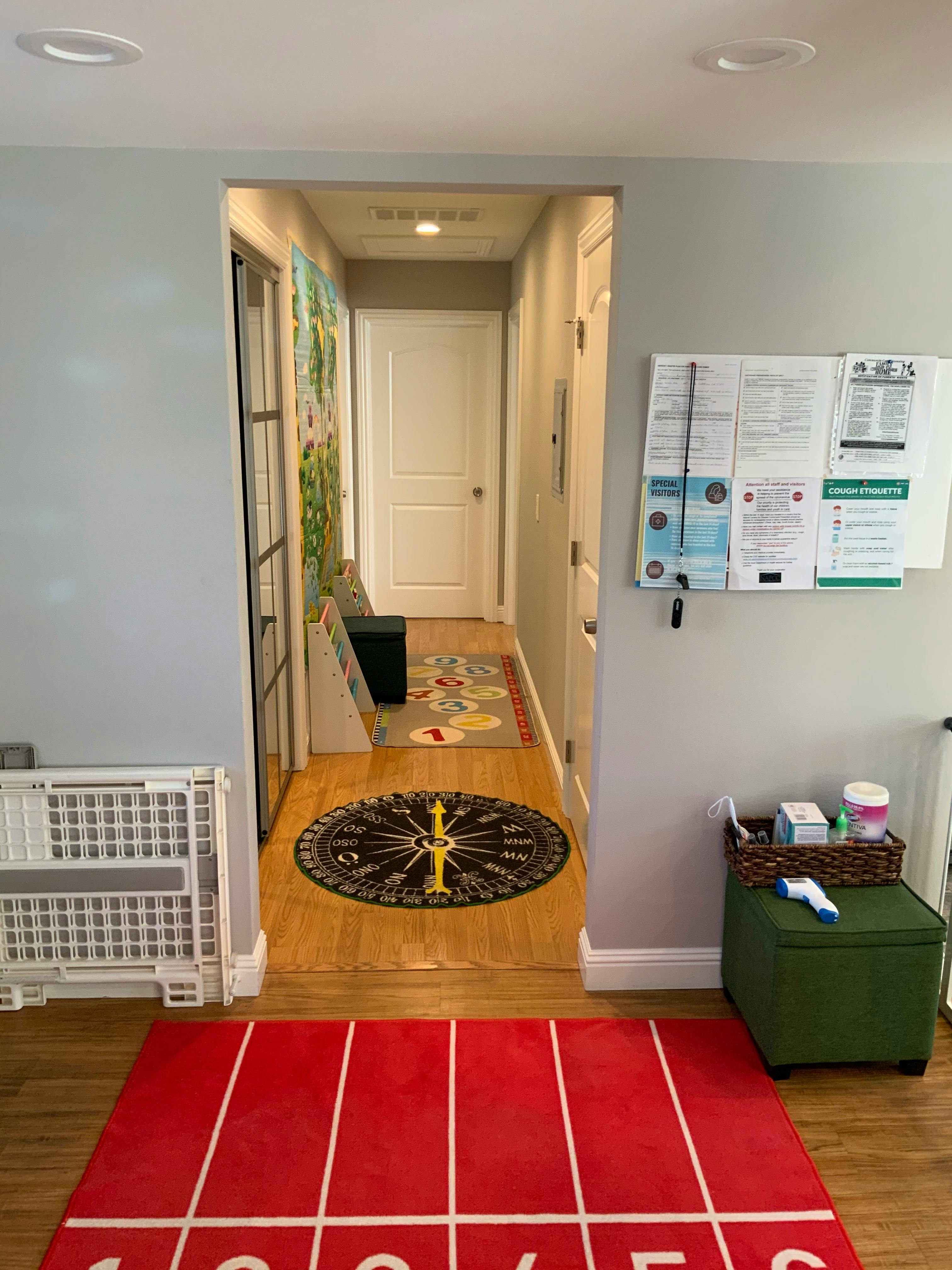 Hallway with a red track rug, a round compass rug, and a bulletin board