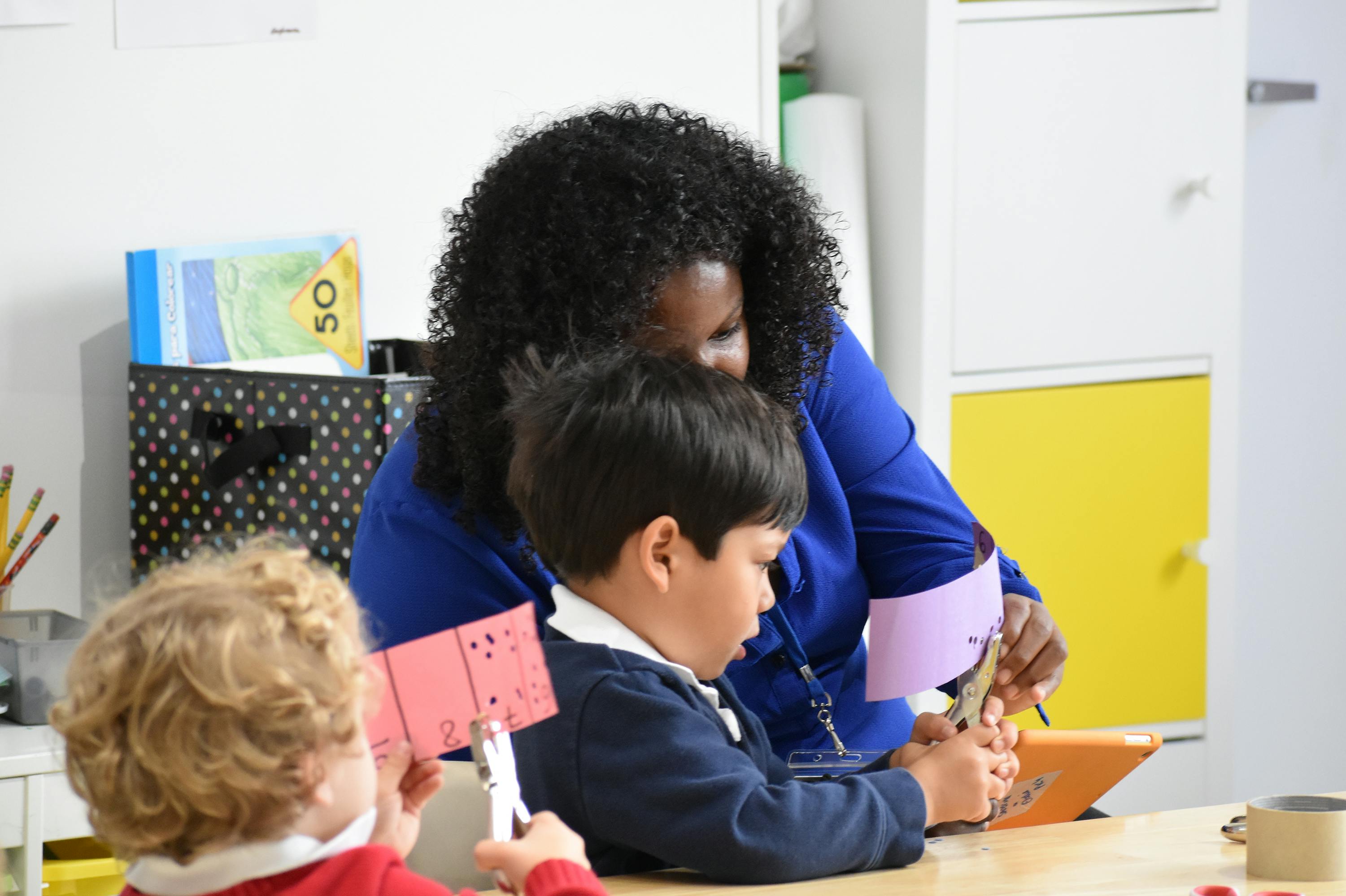 Person helping a child with an activity at a table