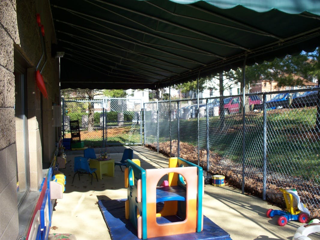 Outdoor play area with sandpit and colorful play equipment under an awning