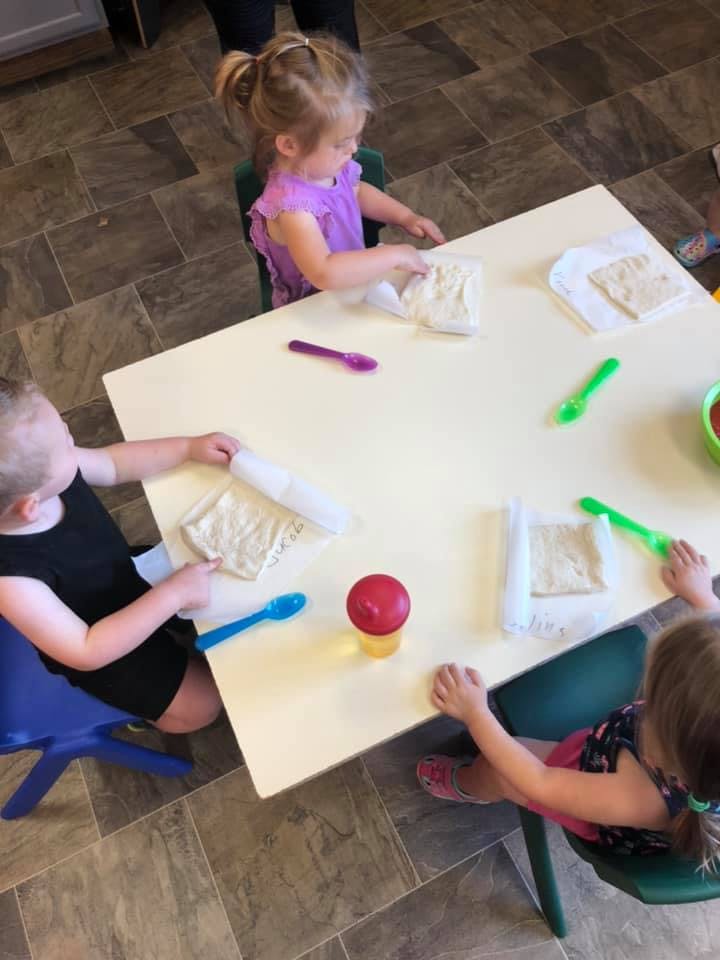 Three children at a table with dough and spoons