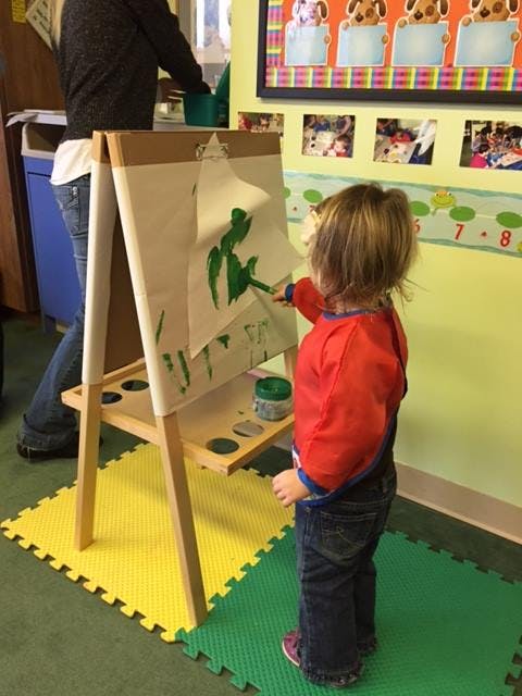 Child painting on an easel in a classroom