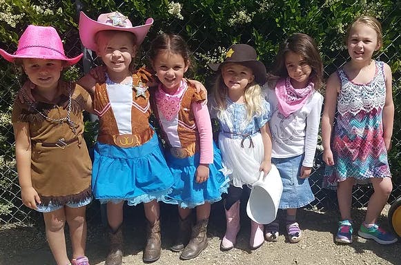 Six children in cowboy and cowgirl costumes standing together