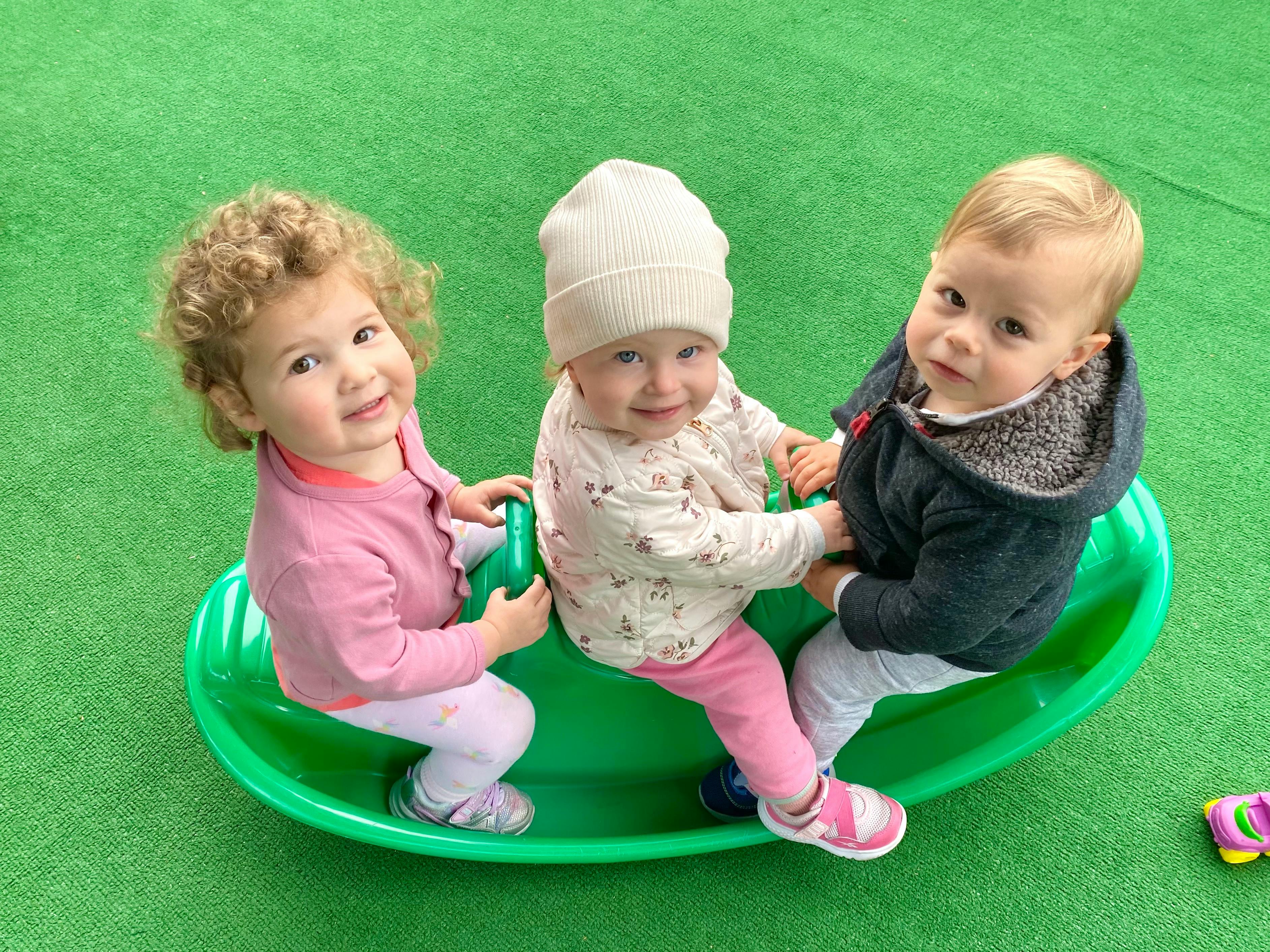Three children on a green seesaw