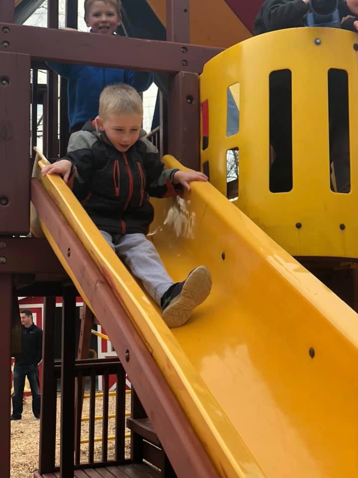 Child going down a yellow slide on a playground