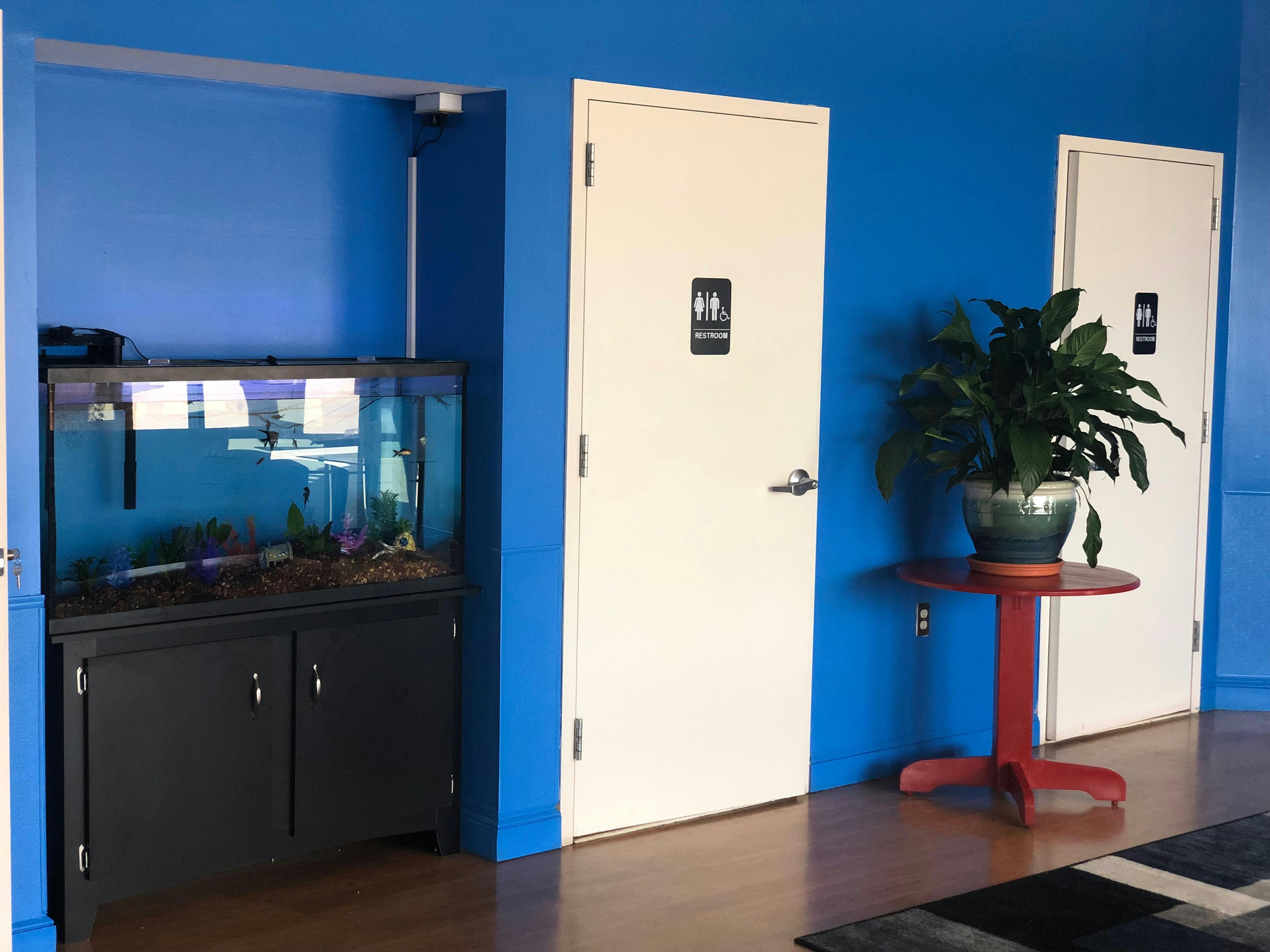 Aquarium next to two doors with restroom signs