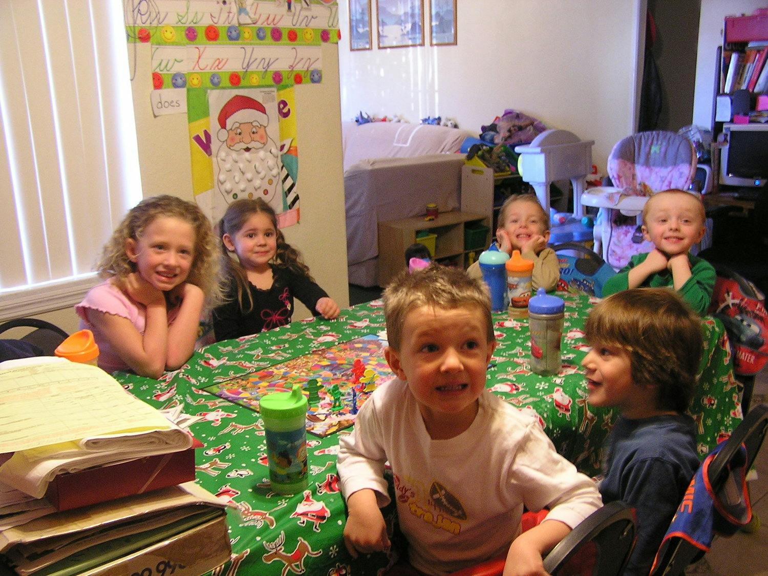 Six children sitting around a table with a green tablecloth