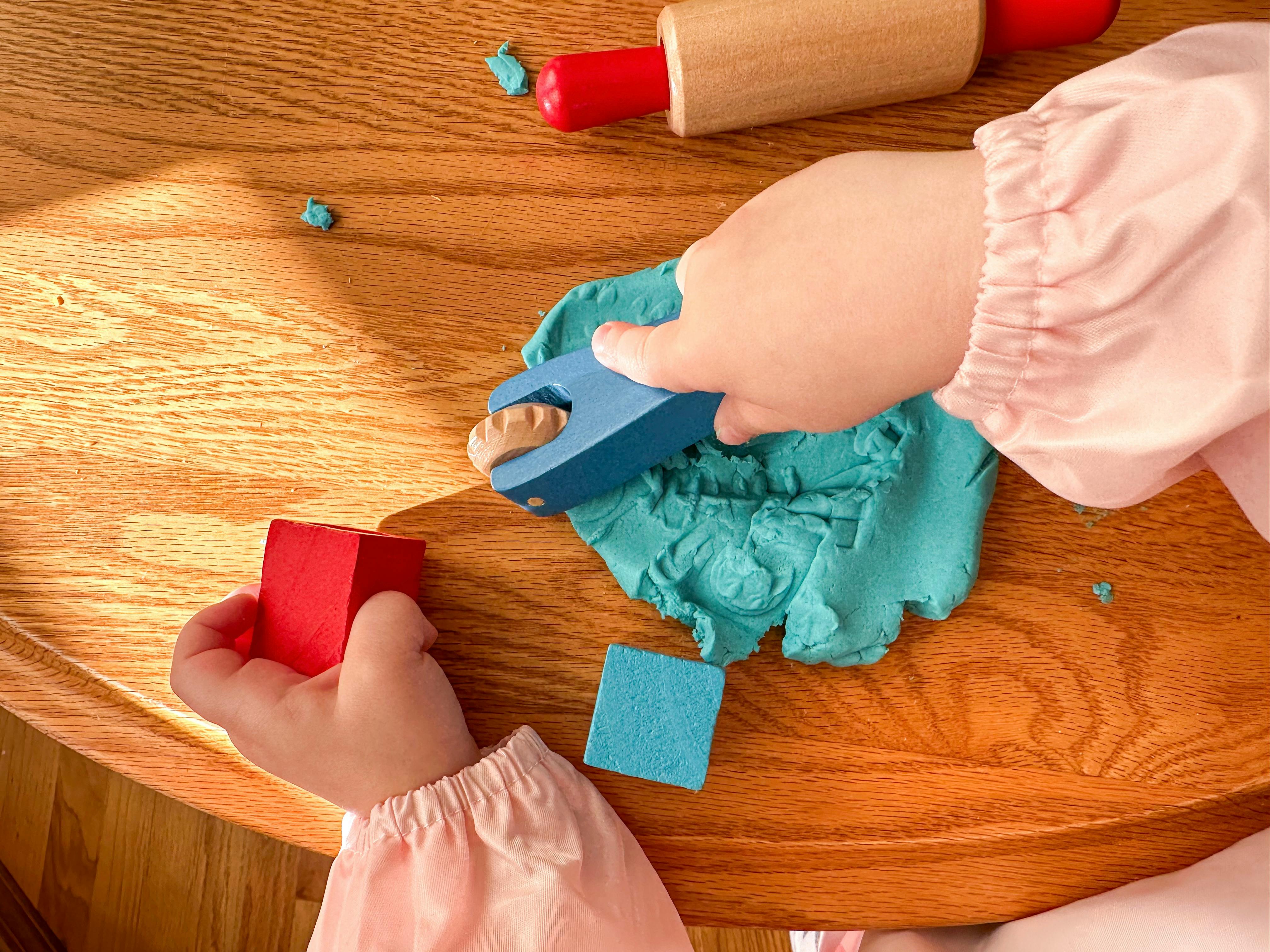 Child playing with blue playdough and blocks