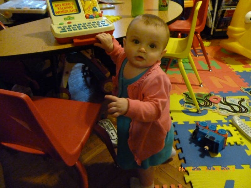 Child standing next to a table with a toy laptop
