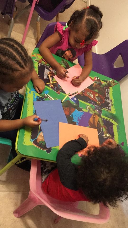 Three children drawing and coloring at a table