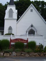 White church building with a steeple and a red sign in front