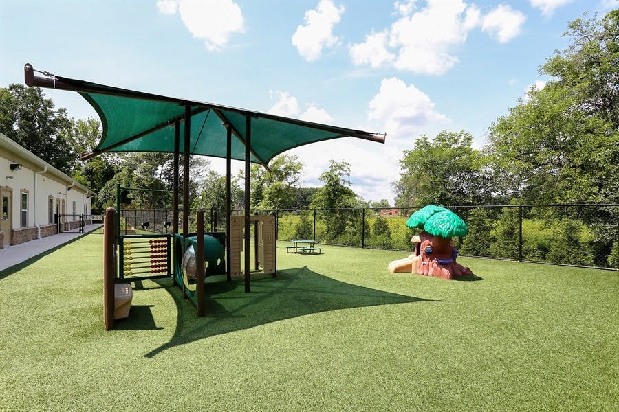 Playground with green shade structure and artificial turf