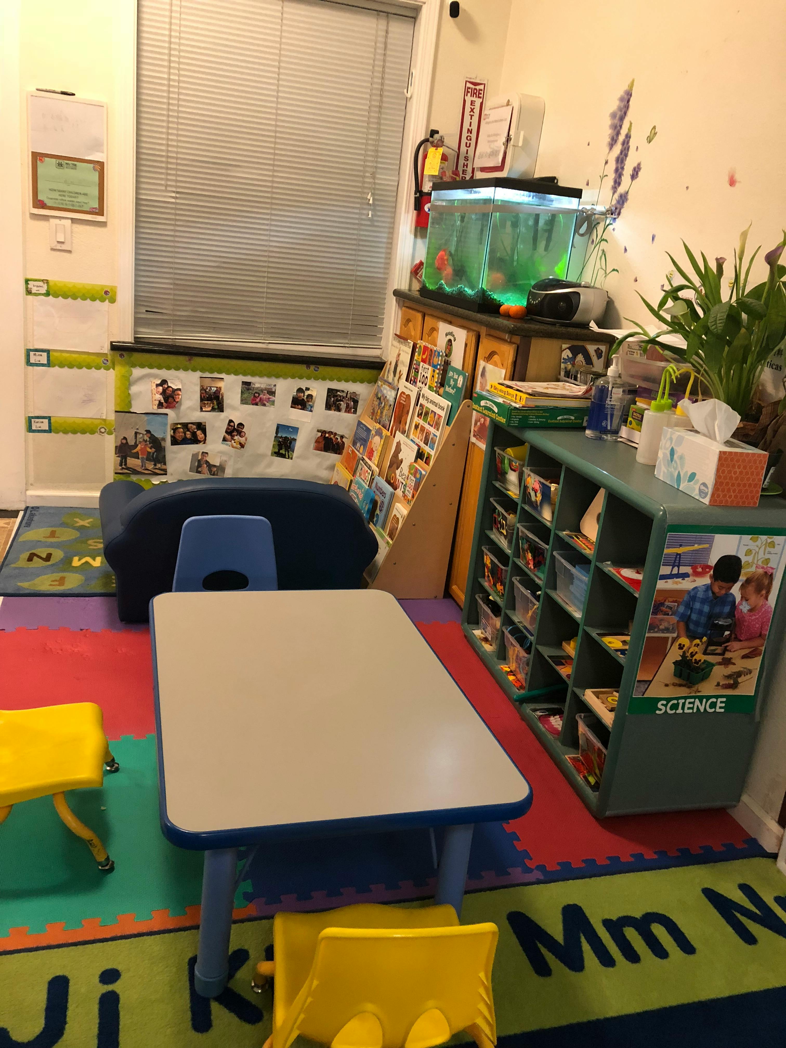 Classroom with small tables and chairs, bookshelves, and a fish tank