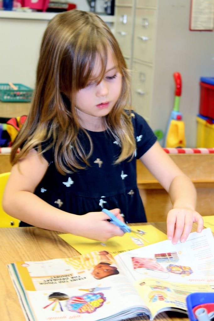 Child cutting paper with scissors at a table
