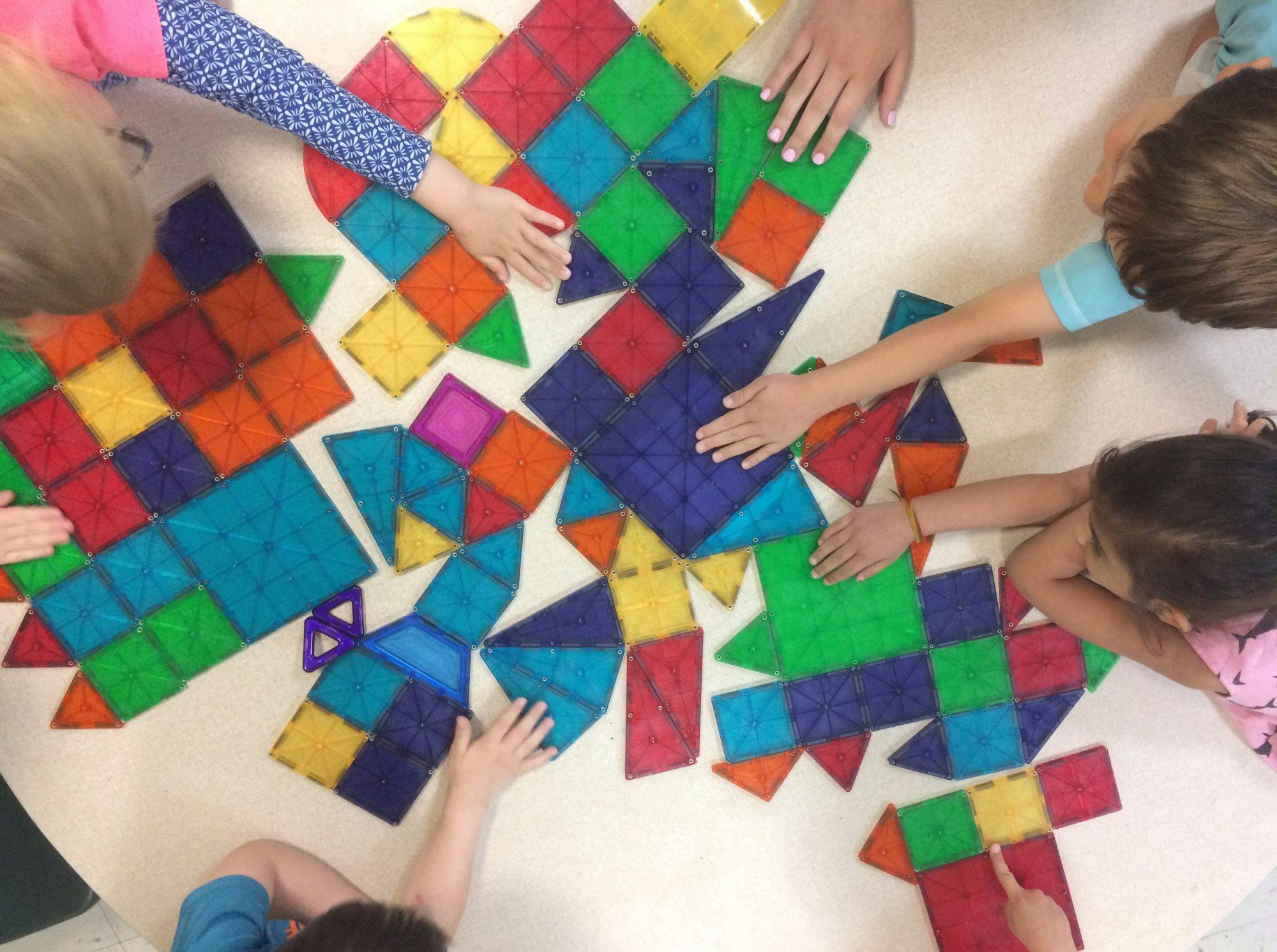 Children playing with colorful magnetic tiles on a table