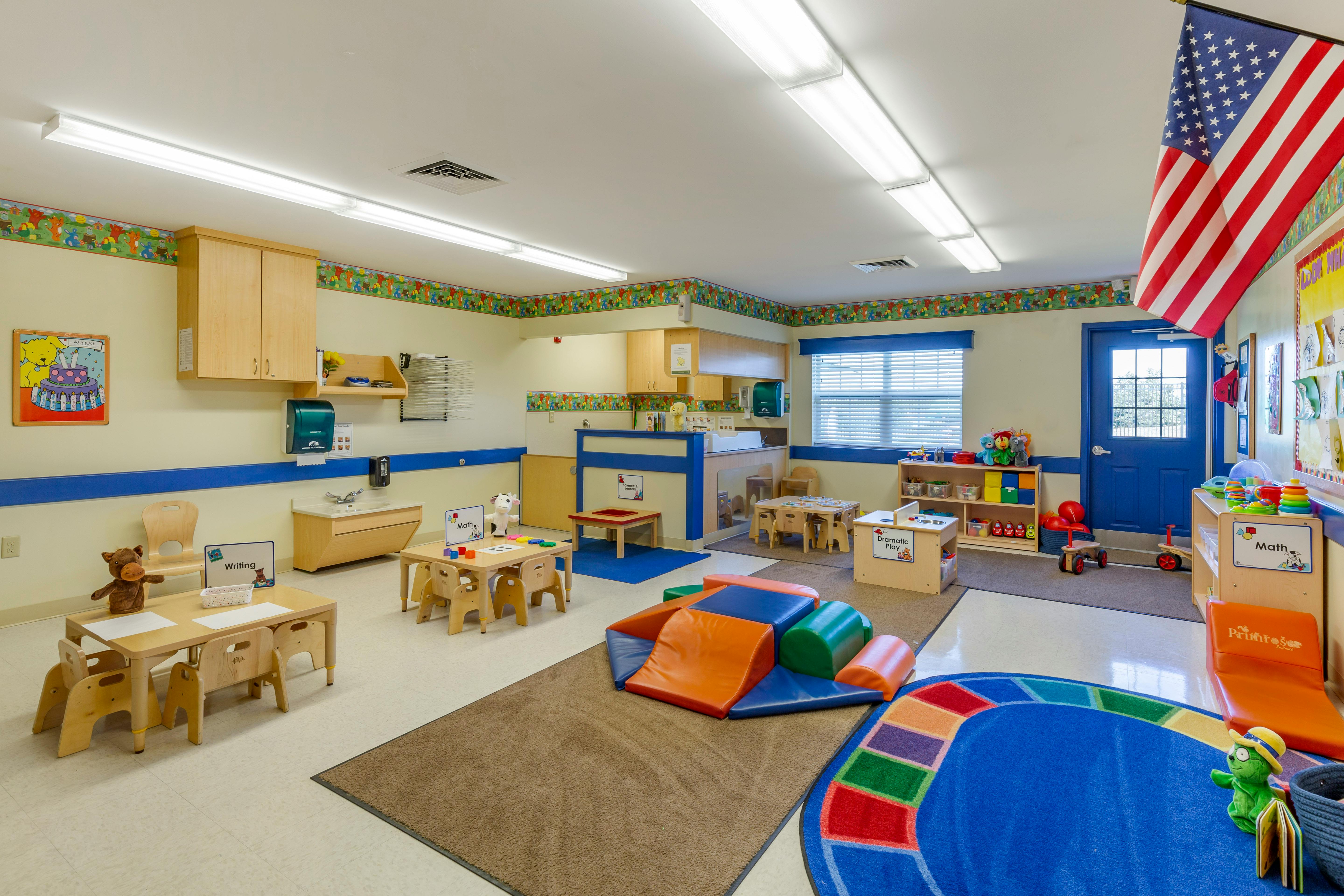 A colorful classroom with child-sized tables, chairs, and play areas