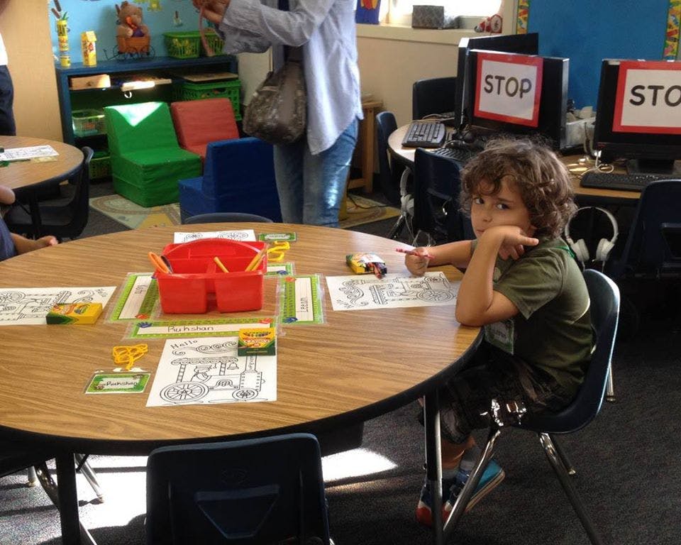 Child sitting at a round table with papers and a red basket
