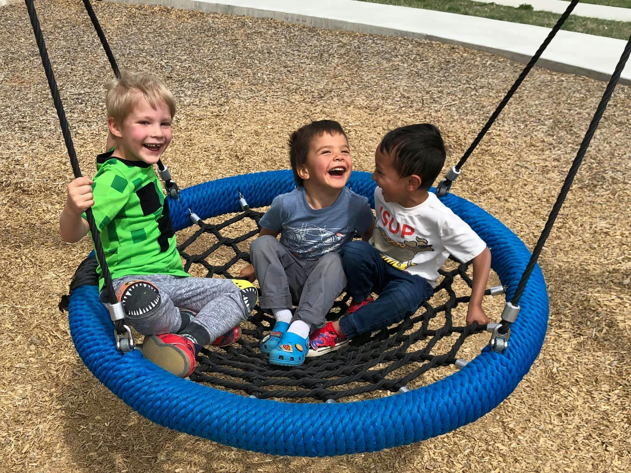 Three children sitting in a round swing