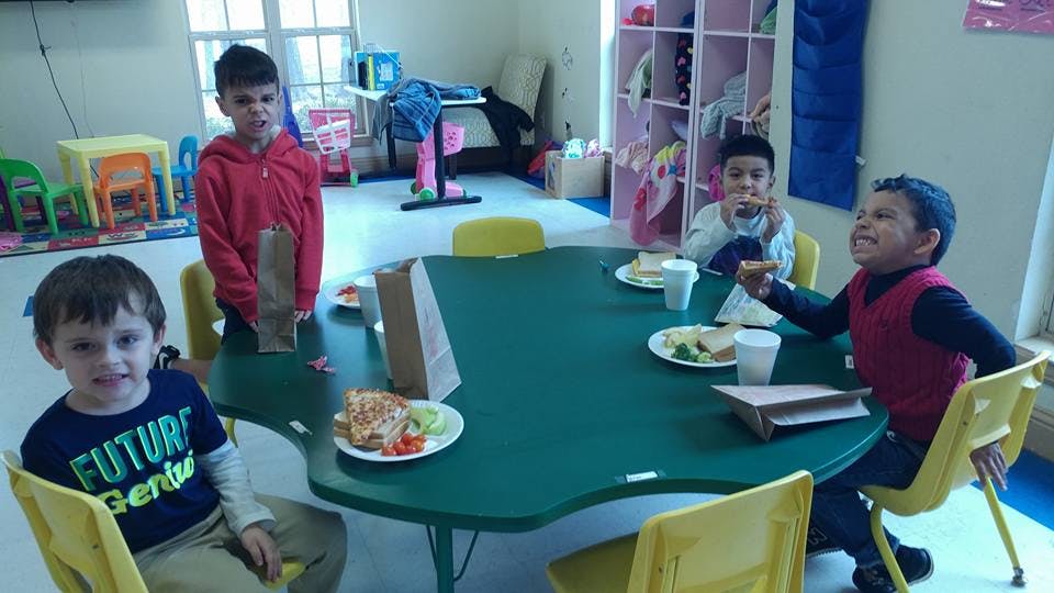 Four children sitting and standing around a table with food