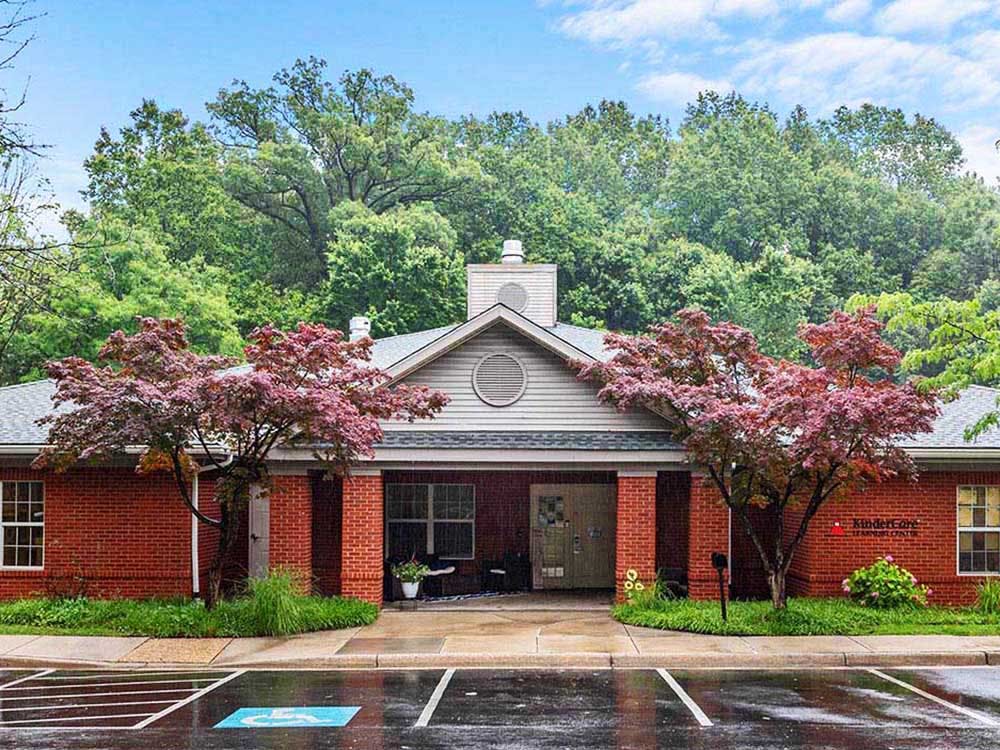 Red brick building with two red-leafed trees in front of the entrance