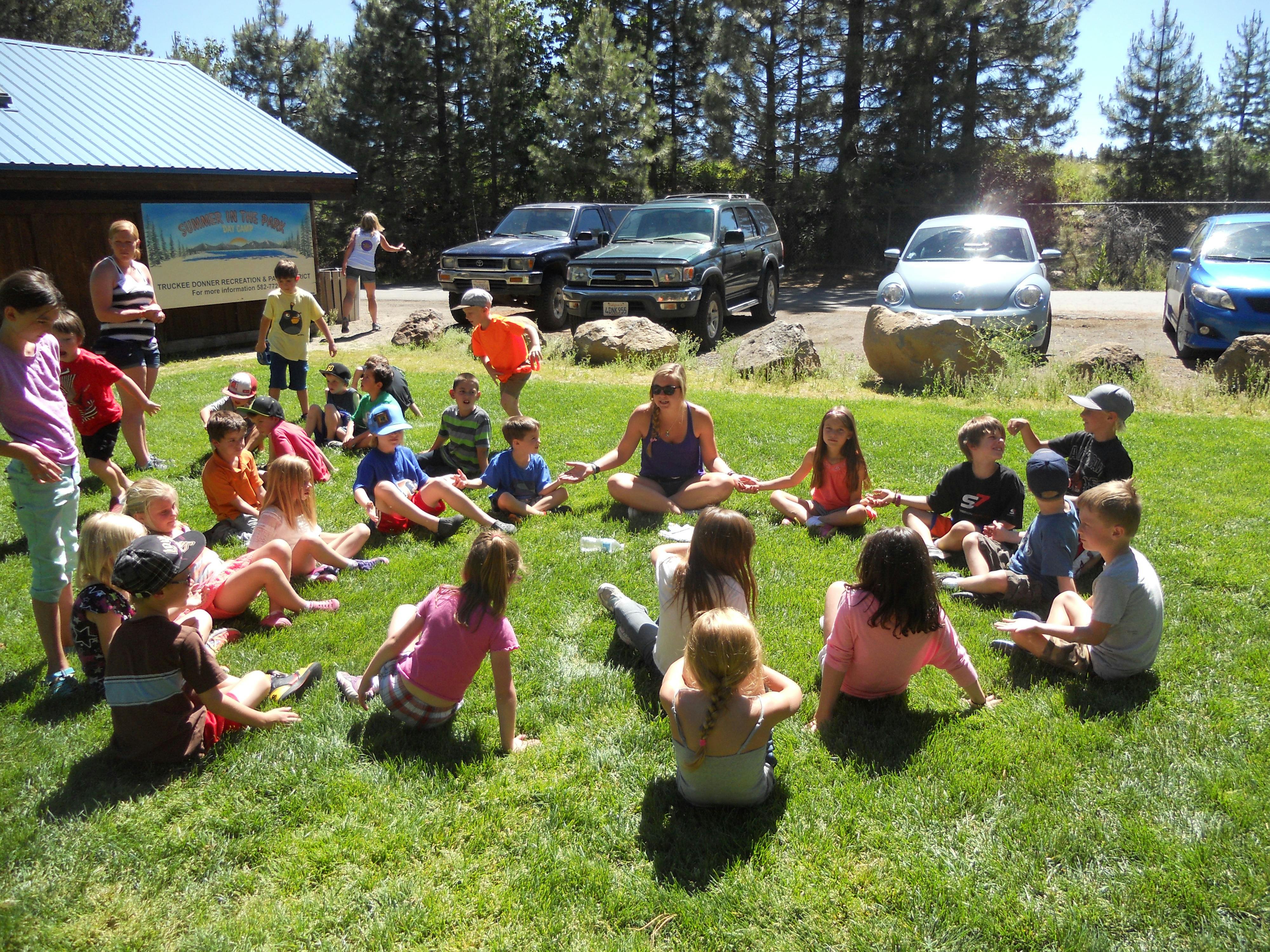 Adults and children sitting in a circle on grass