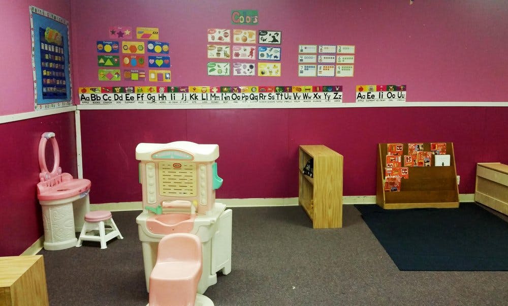 Playroom with pink walls, toy vanity, and toy kitchen